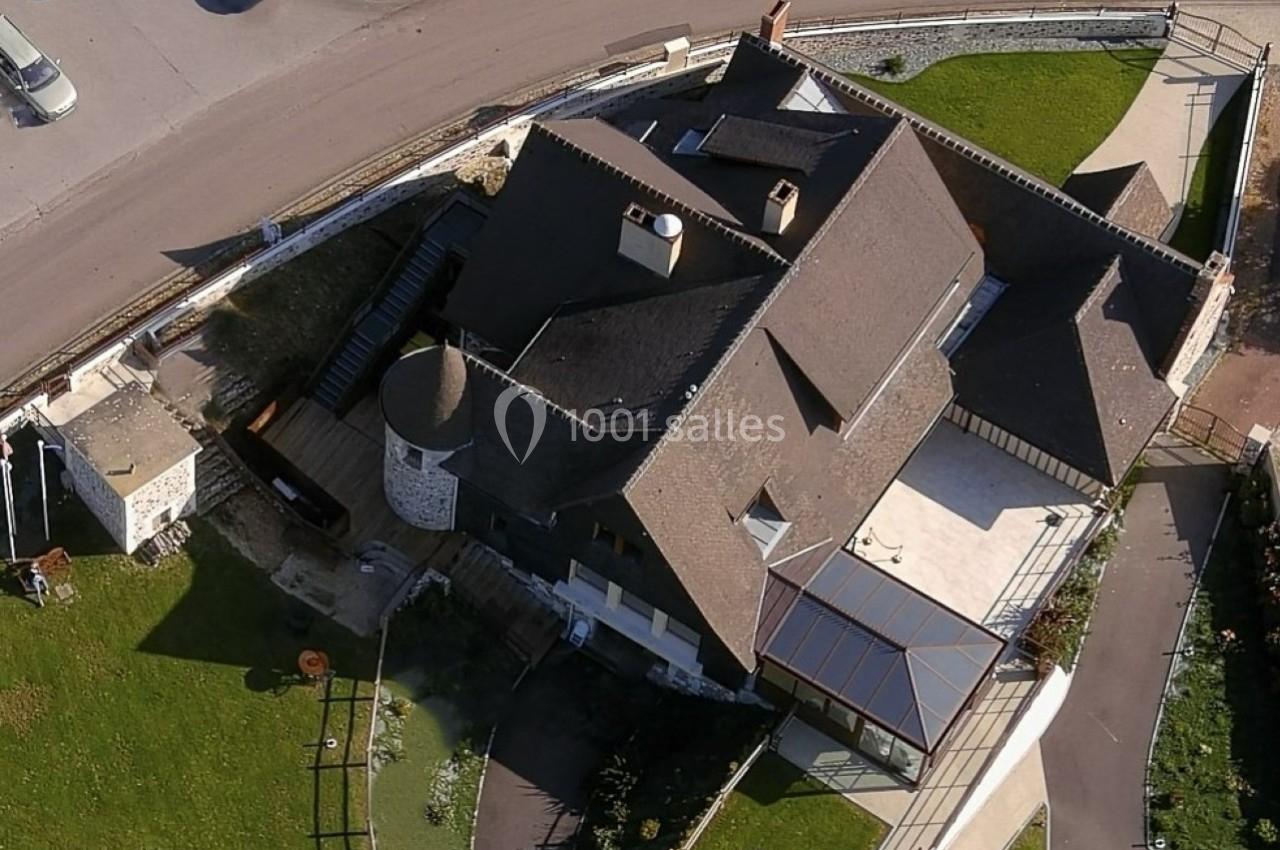 Location salle Saint-Samson-de-la-Roque (Eure) - Manoir Néo Normand #19 Vue aérienne d'un bâtiment en pierre et bois avec une toiture en pente, entouré de pelouses et d'une route.