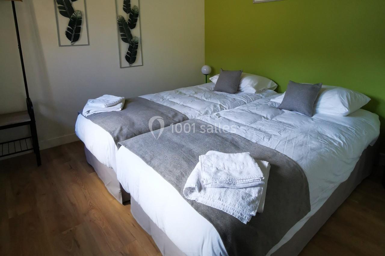 Location salle Saint-Samson-de-la-Roque (Eure) - Manoir Néo Normand #23 Deux lits simples avec draps blancs, couvertures grises et serviettes pliées, dans une chambre au mur vert.