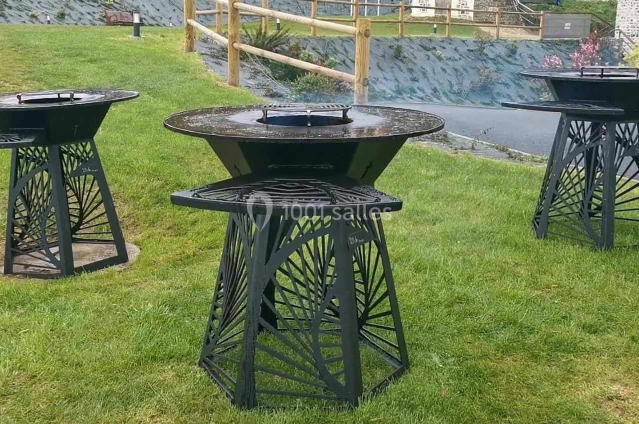 Location salle Saint-Samson-de-la-Roque (Eure) - Manoir Néo Normand #24 Trois barbecues en métal noir au design ajouré, installés sur une pelouse dans un espace extérieur.