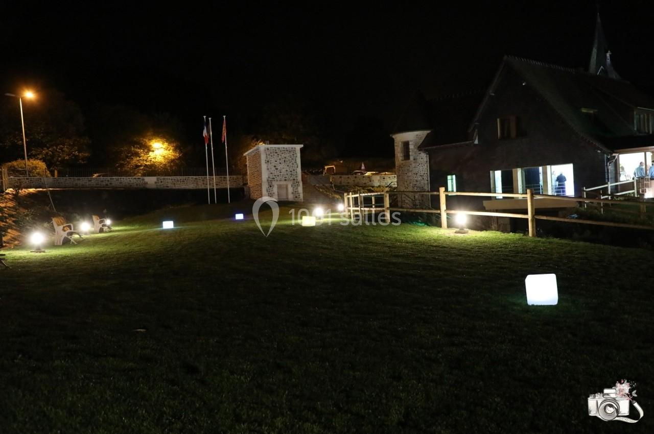 Location salle Saint-Samson-de-la-Roque (Eure) - Manoir Néo Normand #30 Pelouse éclairée par des cubes lumineux colorés devant des bâtiments en pierre et bois, de nuit.