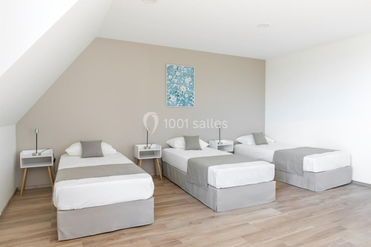 Location salle Saint-Samson-de-la-Roque (Eure) - Manoir Néo Normand #34 Trois lits simples alignés dans une chambre lumineuse avec parquet, murs clairs et tableau décoratif.