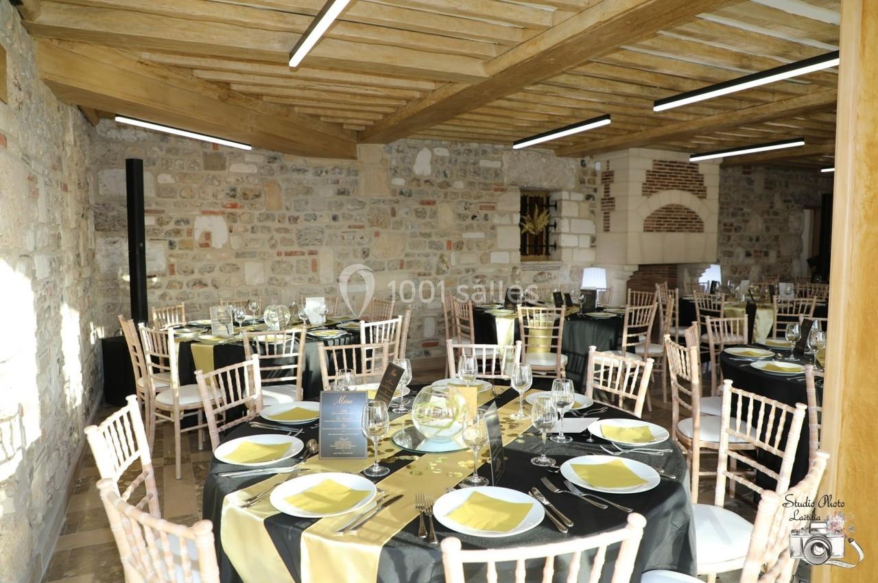 Location salle Saint-Samson-de-la-Roque (Eure) - Manoir Néo Normand #37 Salle de réception en pierre avec tables dressées, nappes noires et jaunes, et chaises en bois clair.