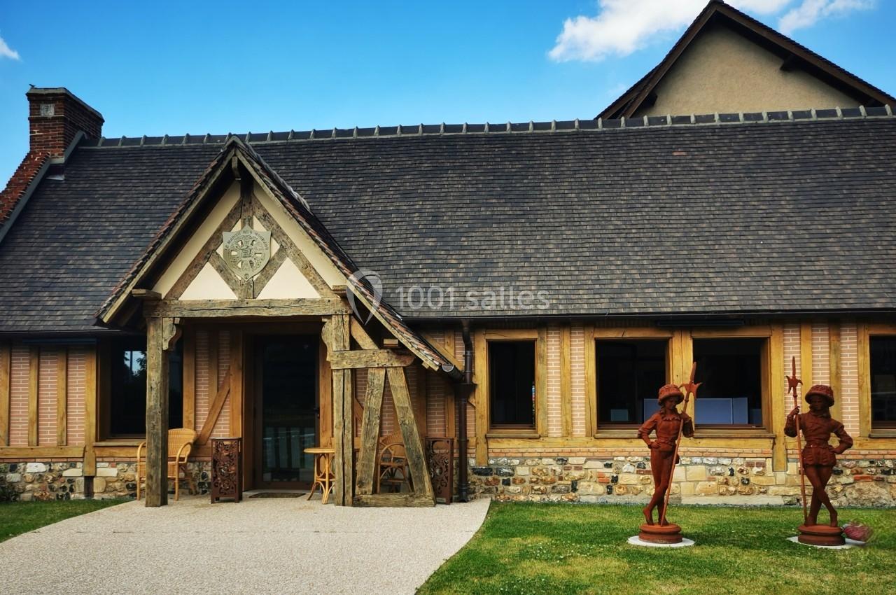 Location salle Saint-Samson-de-la-Roque (Eure) - Manoir Néo Normand #3 Façade d'une maison à colombages avec toit en ardoise, statues décoratives et jardin bien entretenu au premier plan.