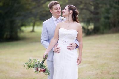 Un couple en tenue de mariage s'enlace dans un jardin verdoyant.