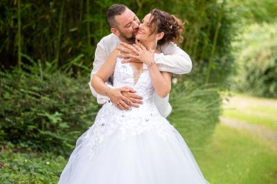 Un couple en tenue de mariage s'enlace dans un jardin verdoyant.