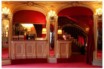 Miniature Espace restauration Entrée d'un théâtre avec comptoir rouge, escalier central, affiches murales et éclairage tamisé.