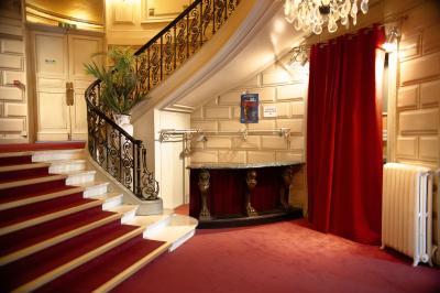 Miniature Le vestiaire Entrée d'un théâtre avec comptoir rouge, escalier central, affiches murales et éclairage tamisé.
