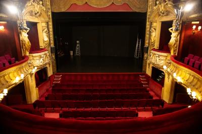 Miniature Théâtre de la Renaissance - L'auditorium Entrée d'un théâtre avec comptoir rouge, escalier central, affiches murales et éclairage tamisé.