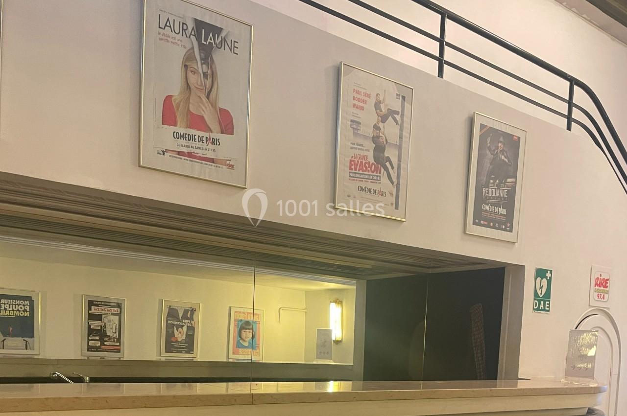 Affiches de spectacles accrochées au mur au-dessus d'un comptoir dans un espace intérieur avec signalétique de sécurité.
