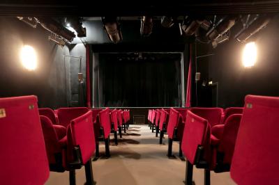 Comptoir rétro dans un hall avec une table et deux chaises, affiches murales et signalétique visible.