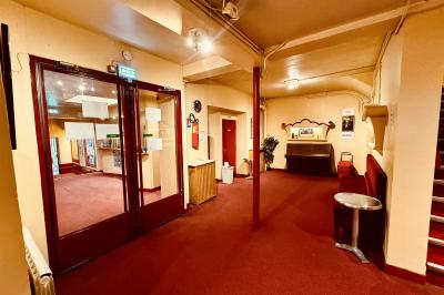 Hall d'entrée d'un théâtre avec affiches de spectacles sur les murs et comptoir d'accueil à gauche.