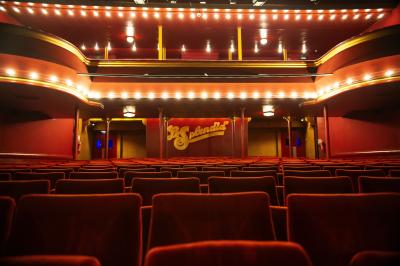 Hall d'entrée d'un théâtre avec affiches de spectacles sur les murs et comptoir d'accueil à gauche.