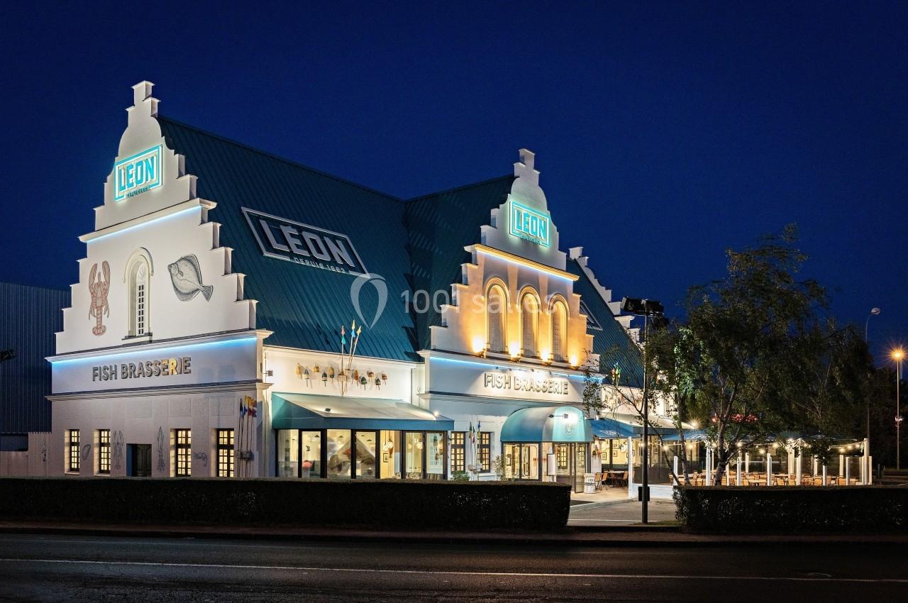 Façade éclairée d'un restaurant au style architectural traditionnel, prise de nuit avec un ciel sombre.