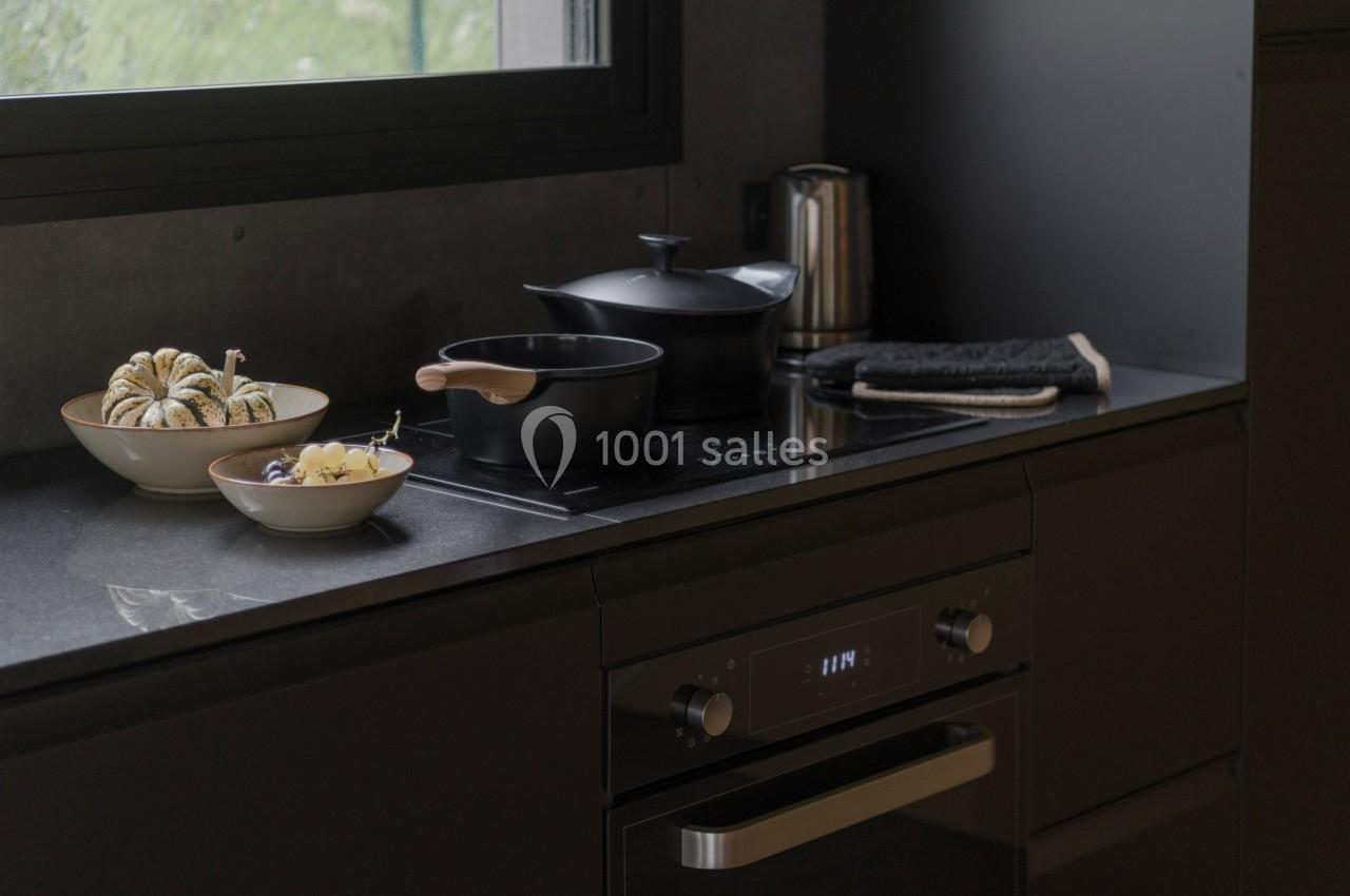 Plan de travail de cuisine moderne avec casseroles, bols de légumes et une bouilloire près d'une fenêtre.