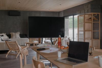 Façade en pierre d'une maison à trois étages avec volets blancs, jardin arboré et allée gravillonnée au premier plan.