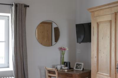 Façade en pierre d'une maison à trois étages avec volets blancs, jardin arboré et allée gravillonnée au premier plan.