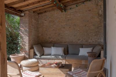 Façade en pierre d'une maison à trois étages avec volets blancs, jardin arboré et allée gravillonnée au premier plan.