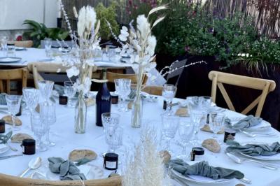 Table dressée en extérieur avec boissons fraîches, carafes d'eau infusée, bouteilles et verres sur une nappe blanche.