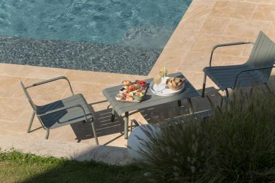 Table dressée en extérieur avec boissons fraîches, carafes d'eau infusée, bouteilles et verres sur une nappe blanche.
