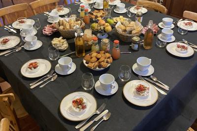 Table dressée en extérieur avec boissons fraîches, carafes d'eau infusée, bouteilles et verres sur une nappe blanche.