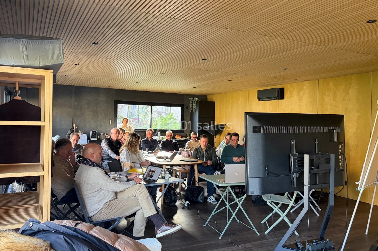 Groupe de personnes assises dans une salle moderne, participant à une réunion ou une formation devant un écran.