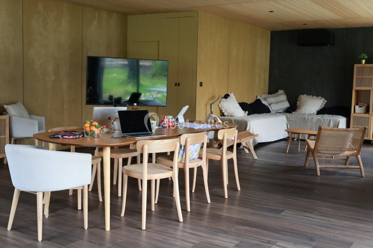Salle de séjour lumineuse avec table en bois, chaises, canapé, télévision et décoration minimaliste.