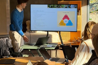 Table dressée en extérieur avec boissons fraîches, carafes d'eau infusée, bouteilles et verres sur une nappe blanche.