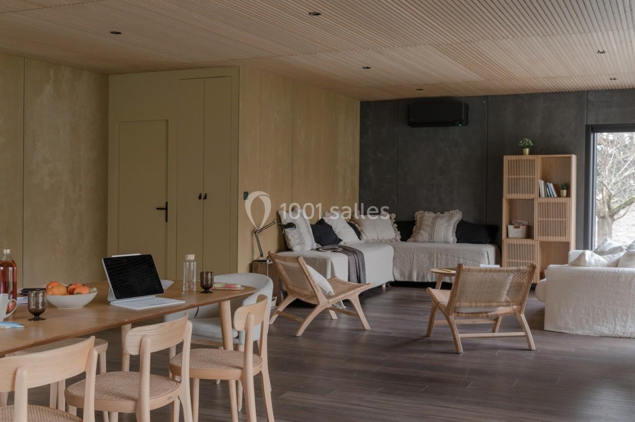 Salle de séjour moderne avec mobilier en bois clair, canapés blancs, étagères et lumière naturelle.