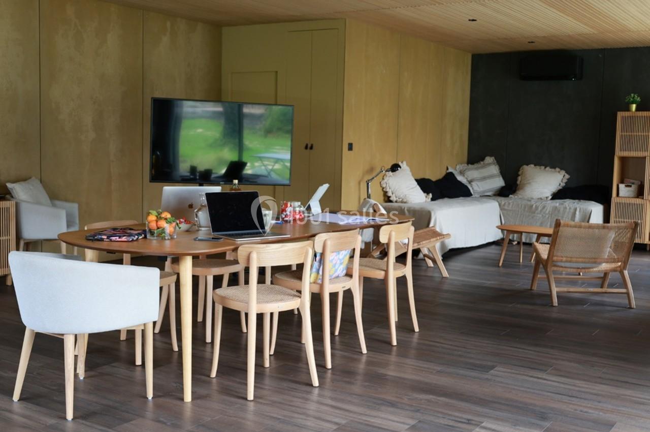 Salle de séjour lumineuse avec table en bois, chaises, canapé, télévision et décorations modernes.