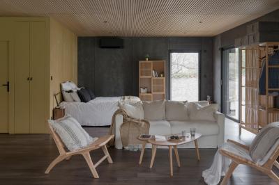 Canapé beige avec coussins blancs et noirs, plaid gris, lampe de bureau noire et table d'appoint en bois.