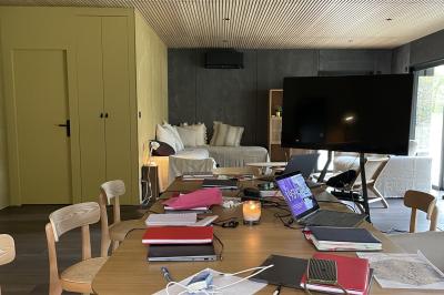 Canapé beige avec coussins blancs et noirs, plaid gris, lampe de bureau noire et table d'appoint en bois.