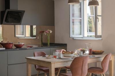 Canapé beige avec coussins blancs et noirs, plaid gris, lampe de bureau noire et table d'appoint en bois.