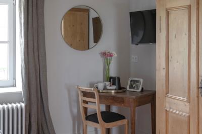 Canapé beige avec coussins blancs et noirs, plaid gris, lampe de bureau noire et table d'appoint en bois.