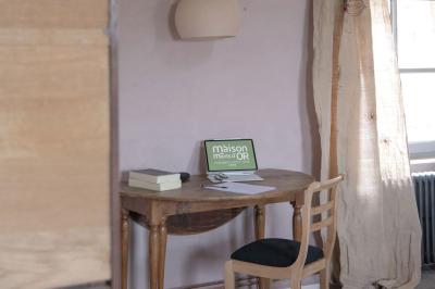Canapé beige avec coussins blancs et noirs, plaid gris, lampe de bureau noire et table d'appoint en bois.
