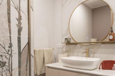 Canapé beige avec coussins blancs et noirs, plaid gris, lampe de bureau noire et table d'appoint en bois.