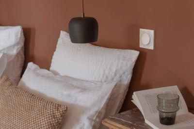 Canapé beige avec coussins blancs et noirs, plaid gris, lampe de bureau noire et table d'appoint en bois.