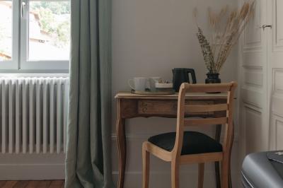 Canapé beige avec coussins blancs et noirs, plaid gris, lampe de bureau noire et table d'appoint en bois.
