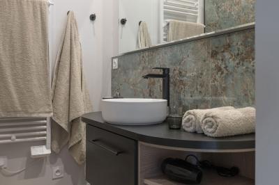 Canapé beige avec coussins blancs et noirs, plaid gris, lampe de bureau noire et table d'appoint en bois.