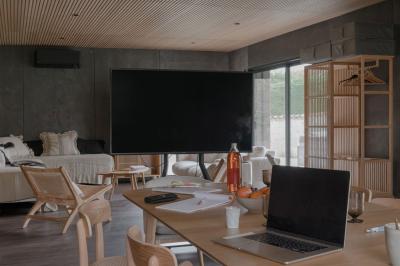Canapé beige avec coussins blancs et noirs, plaid gris, lampe de bureau noire et table d'appoint en bois.