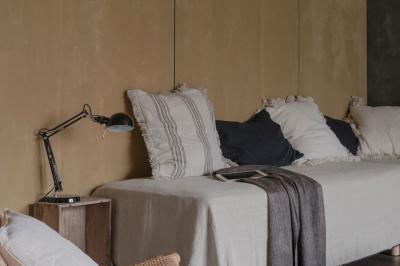 Canapé beige avec coussins blancs et noirs, plaid gris, lampe de bureau noire et table d'appoint en bois.