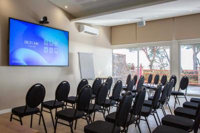 Miniature Location salle Saint-Cyprien (Pyrénées-Orientales) - Grand Hôtel du Lido #3 Bureau en bois avec lampe allumée, chaise colorée et vue sur un balcon donnant sur des arbres et des bâtiments.