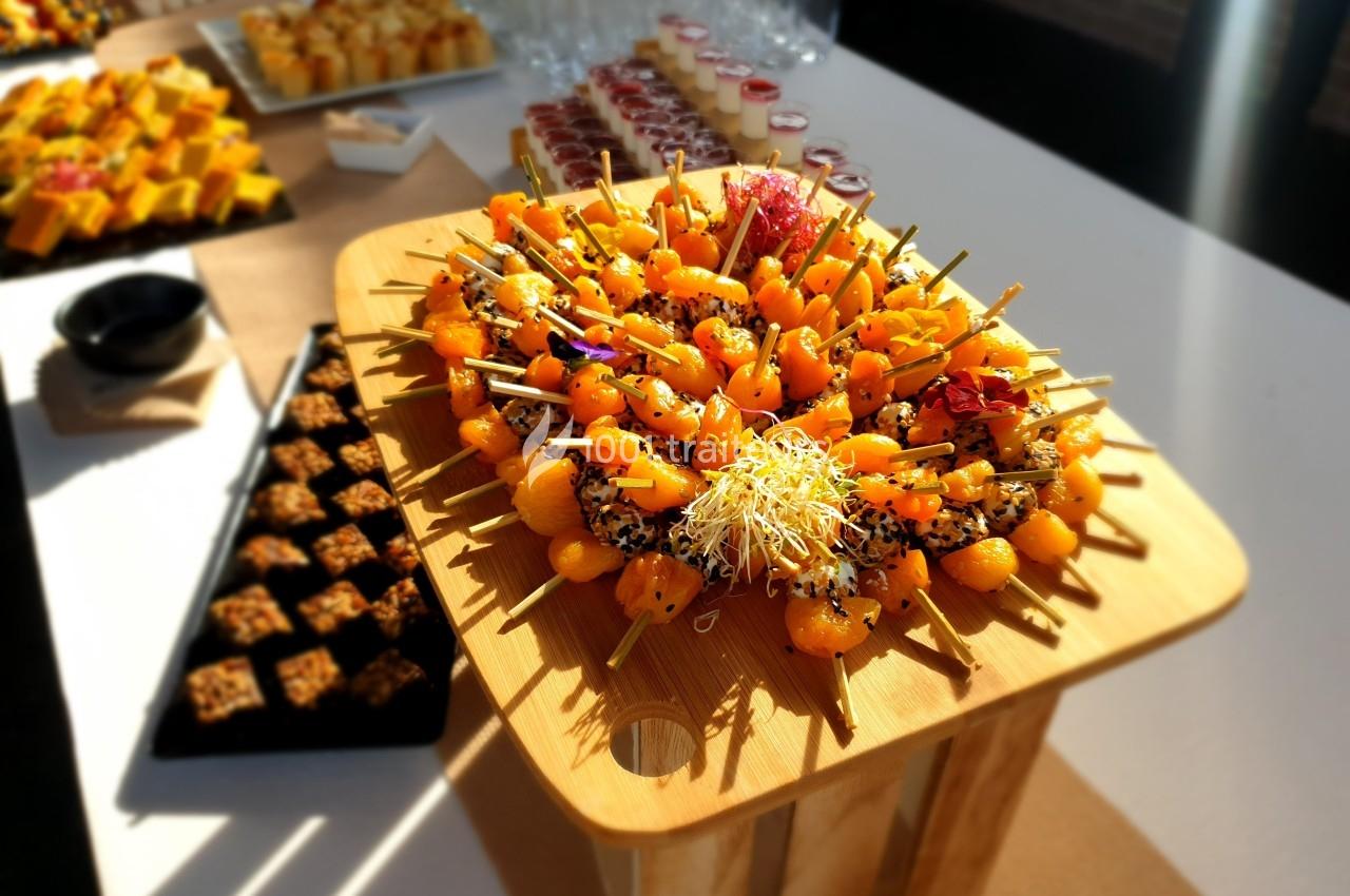 Plateau en bois garni de brochettes apéritives colorées, entouré de desserts et verrines sur une table de buffet.