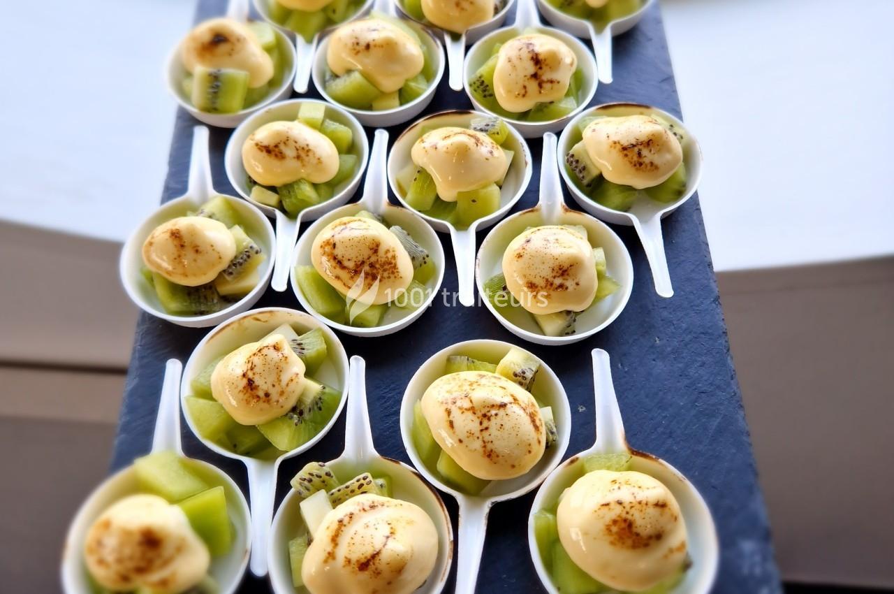 Coupes individuelles contenant des morceaux de kiwi frais et une boule de crème, saupoudrées d'épices.