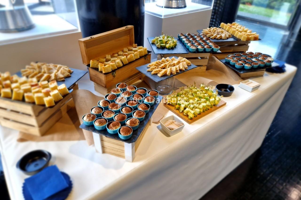 Table de buffet avec une variété de desserts et amuse-bouches présentés sur des plateaux en bois et ardoise.