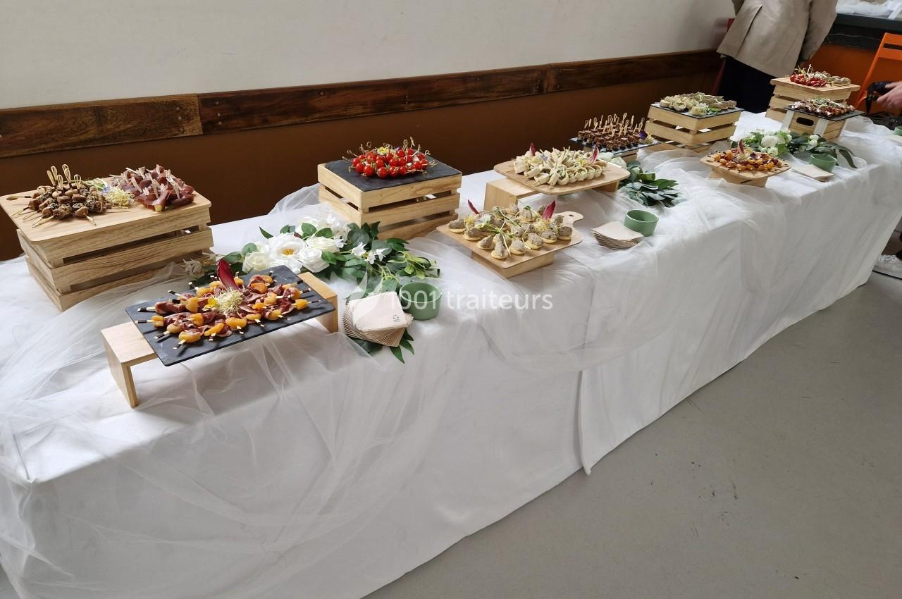Buffet de canapés variés présentés sur des plateaux en bois, disposés sur une table recouverte d'une nappe blanche.