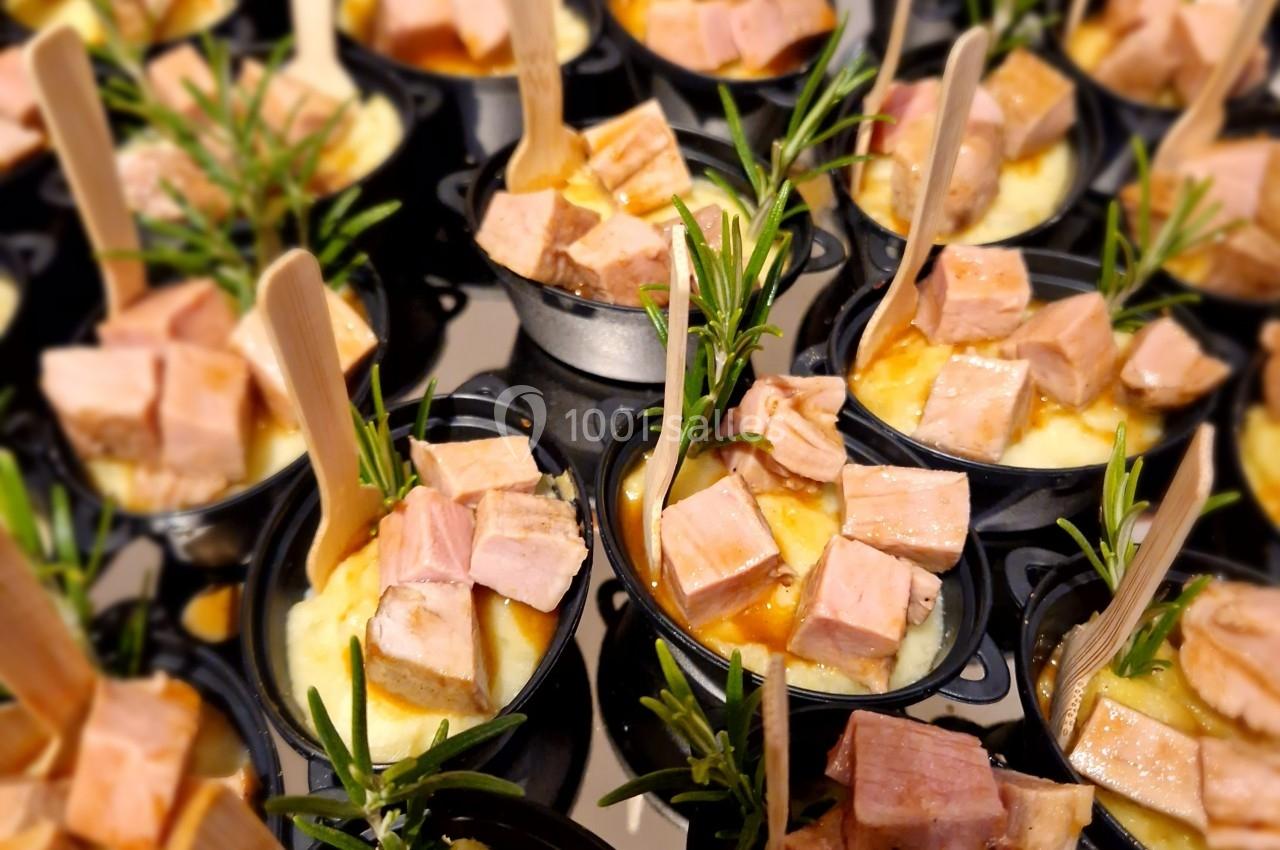 Petits plats individuels contenant de la purée, des morceaux de viande et des brins de romarin, avec des cuillères en bois.