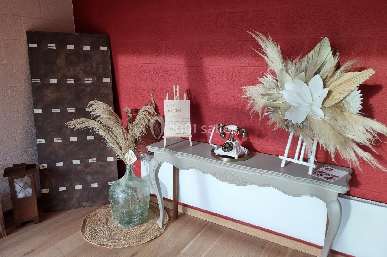 Console beige décorée avec un téléphone vintage, des bouquets de pampas et une planche d'échantillons devant un mur rouge.