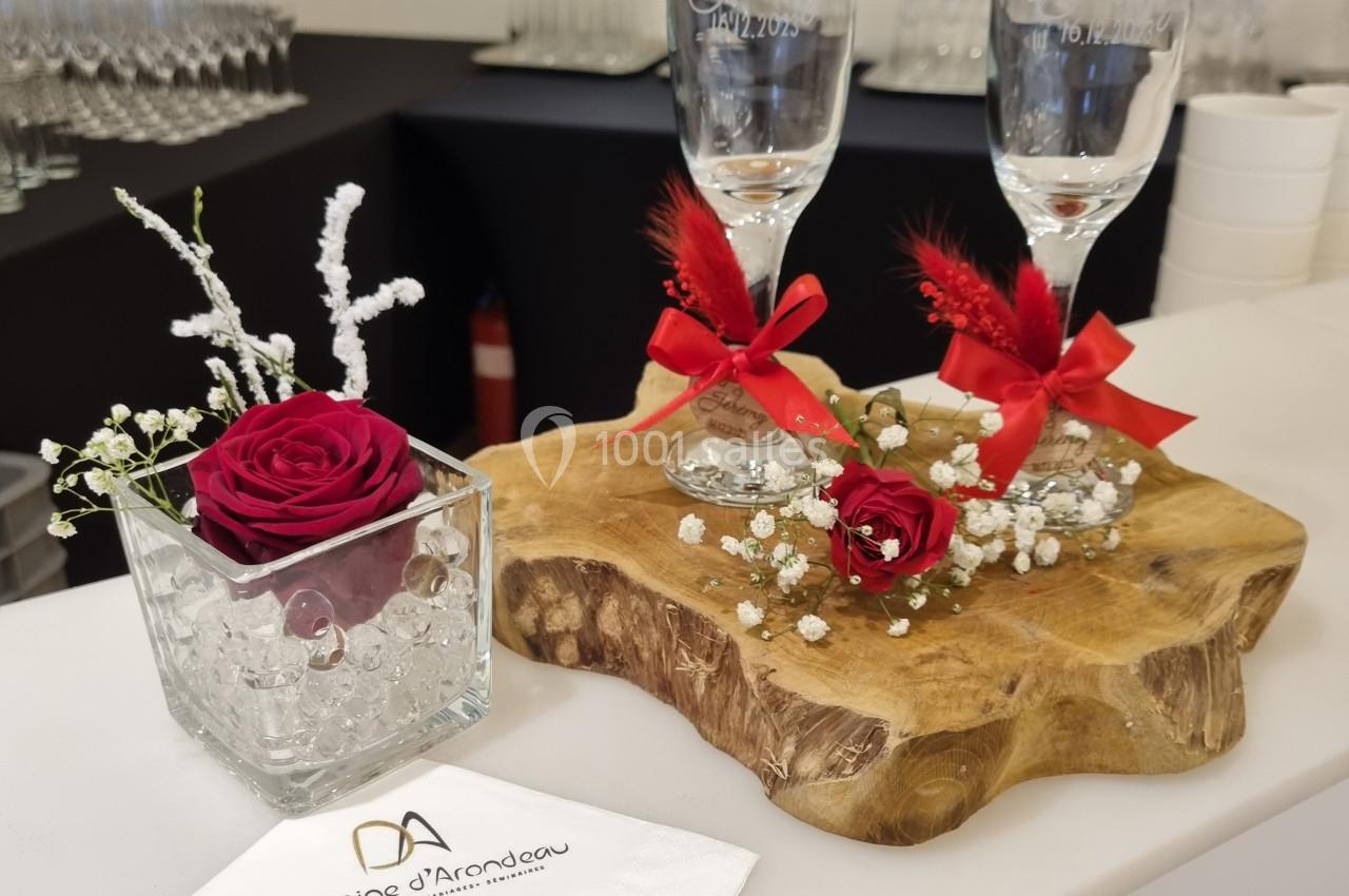 Deux flûtes décorées sur une planche en bois, avec roses rouges, gypsophile et serviette personnalisée.