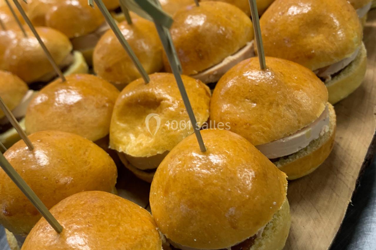 Mini-burgers dorés garnis, présentés sur un plateau en bois avec des pics en bambou.