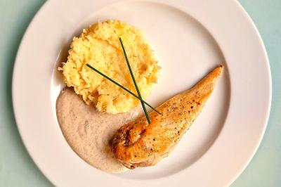 Plat dressé avec une base de viande effilochée, purée de pommes de terre, feuilles de salade et sauce en décoration.